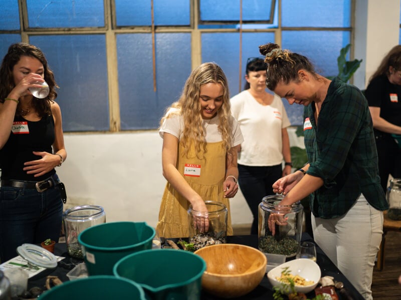 A group of women smiling and building terrariums at a terrarium class in Sydney